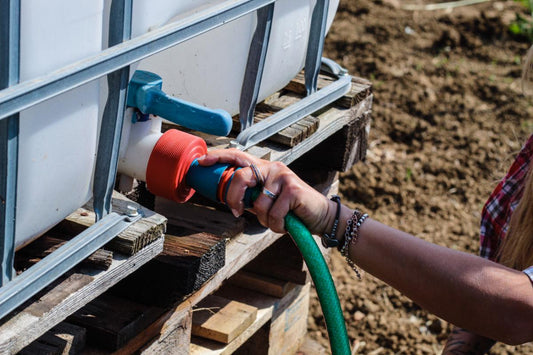 Raccordo TechOrto montato sulla valvola di una cisterna IBC e collegato al tubo di irrigazione.