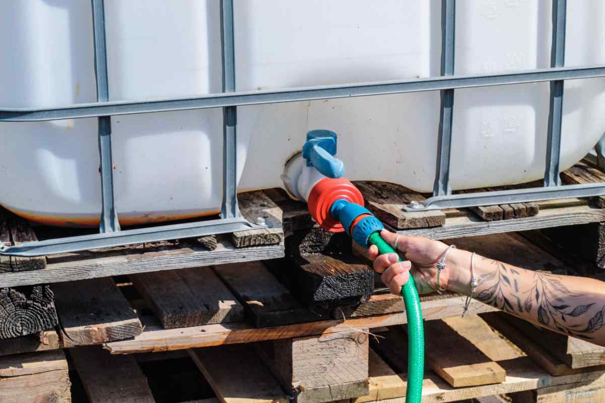 Raccordo TechOrto per cisterna IBC collegato a tubo di irrigazione e portagomma senza perdite.